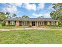 Charming ranch style home with a brick and wood facade and a large, green front yard at 1071 Deer Run Dr, Winter Springs, FL 32708