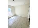 A bright bedroom featuring tiled floors, a window for natural light, and fresh paint at 1557 Venice Ln, Davenport, FL 33896