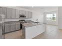 Bright kitchen featuring gray cabinets, a center island, granite counters, and stainless steel appliances at 1580 Gardiner St, Haines City, FL 33844