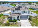 Aerial view of a modern home with solar panels, a two-car garage, and landscaped front yard near a pond at 242 White Heron Way, St Cloud, FL 34772