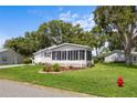 Quaint home with a beautiful green lawn, complete with a decorative fire hydrant and lush landscaping at 25333 Casa Del Lago Ln, Leesburg, FL 34748