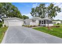 Inviting home with a spacious driveway leading to a garage, complemented by a charming screened-in porch at 25333 Casa Del Lago Ln, Leesburg, FL 34748