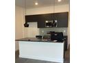 Bright kitchen features dark cabinetry, modern pendant lights, and an island with a sleek countertop at 3213 Energy Dr, Kissimmee, FL 34747