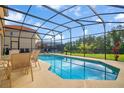 Screened in backyard pool with patio furniture and a serene view of lush green trees at 381 Cabello Dr, Davenport, FL 33837
