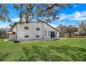 Back view of two-story home with large, grassy yard, patio, and sliding glass doors at 40140 Swift Rd, Eustis, FL 32736