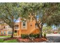 Three-story townhome with stairs leading to the second level, lush landscaping, and blue sky at 12414 Baleria Cv # 104, Orlando, FL 32837