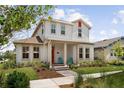 Beautifully landscaped two-story home featuring a red door and shutter, with inviting blue chairs on the porch at 13208 Leggett Aly, Orlando, FL 32827