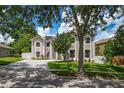 Two-story home boasting large windows and manicured landscaping, partly obscured by the shade of a mature tree at 1706 Cheltenborough Dr, Orlando, FL 32835