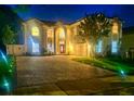 Exterior view of a two-story home at night featuring well-lit landscaping and a long paved driveway at 1706 Cheltenborough Dr, Orlando, FL 32835
