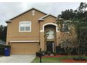 Two-story home with tan exterior and a well-maintained front lawn and landscaping at 2020 Rushden Dr, Ocoee, FL 34761