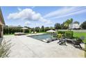 Backyard with a modern pool, lounge chairs, umbrella, lush landscaping, and privacy fence at 2118 Whiting Trl, Orlando, FL 32820