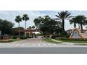 Community entrance with palm trees, lush landscaping, and decorative details at 3065 Yellow Lantana Ln, Kissimmee, FL 34747