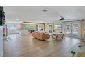Spacious open-concept living area featuring wood-look floors, modern furnishings, and access to the pool at 4390 Carolwood St, Orlando, FL 32812
