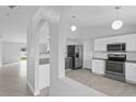 Modern kitchen with stainless steel appliances and sleek white cabinets and granite countertop at 446 Arkansas Ct, Poinciana, FL 34759