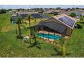 Aerial view of a home with a screened-in pool and solar panels in a neighborhood at 456 Old Bridge Cir, Davenport, FL 33897