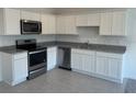 Well-lit kitchen with stainless steel appliances, granite countertops, and white cabinetry at 497 Madison Dr, Davenport, FL 33837