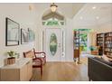 Bright foyer with a high ceiling, decorative white door, wood floors, and views into the living room at 985 N Lake Claire Cir, Oviedo, FL 32765