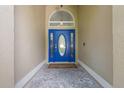 Inviting entryway showcasing a vibrant blue front door with decorative glass and stylish stone flooring at 985 N Lake Claire Cir, Oviedo, FL 32765