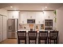 Modern white kitchen featuring stainless steel appliances, a breakfast bar, and stylish barstools at 112 Avocado Ave, Sanford, FL 32771
