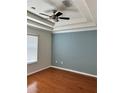 Bedroom featuring a tray ceiling, ceiling fan, and wood flooring for a comfortable living space at 14147 Mailer Blvd, Orlando, FL 32828