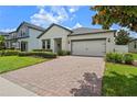 Attractive single-story home with brick driveway, tidy landscaping, and attached two-car garage at 2210 Romanum Dr, Winter Garden, FL 34787