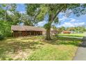View of the brick home from the yard with a large tree providing ample shade at 236 Longhorn Dr, Apopka, FL 32712