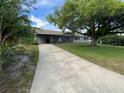View of an exterior of a house featuring a long driveway surrounded by grass and mature trees at 2648 Amsden Rd, Winter Park, FL 32792