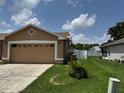 View of the home's side yard, showcasing the attached garage and green lawn at 2693 Maxwell W Ct, Kissimmee, FL 34743