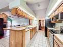 Functional kitchen featuring wood cabinets, white tile flooring, and a breakfast bar open to the living area at 6970 Knightswood Dr, Orlando, FL 32818