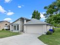 Single-story home featuring a well-manicured lawn and a two-car garage at 826 Long Bay Ct, Kissimmee, FL 34741