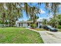 Inviting exterior view of a home with a lush green lawn, mature trees, and a well-lit driveway at 1000 Sal St, Ocoee, FL 34761