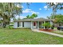 Cozy single-Gathering home featuring a manicured lawn, mature trees, and a charming covered entryway at 1000 Sal St, Ocoee, FL 34761