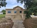 Single-story home with concrete steps leading to the front door under a partly cloudy sky at 1020 E Main St, Haines City, FL 33844