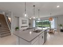 Modern kitchen with center island, stylish pendant lighting, and adjacent living area with outdoor views at 17319 Million Lakes Ct, Clermont, FL 34714