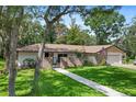 Charming single-story home featuring a brick facade, lush green lawn, and mature trees under a bright, sunny sky at 203 N Sweetwater Blvd, Longwood, FL 32779
