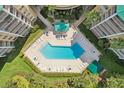 Aerial view of the complex's geometric pool, surrounded by greenery and lounge chairs at 4650 Links Village Dr # B103, Ponce Inlet, FL 32127