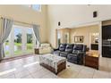 Bright living room with high ceilings, tile floors, furniture, and large windows overlooking the pond at 9207 Busaco Park Way, Winter Garden, FL 34787