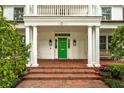 Inviting entrance with a bright green door, brick pathway, white columns, and classic wall-mounted lanterns at 1011 Lake Davis Dr, Orlando, FL 32806