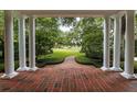Covered porch with brick flooring and white columns framing a serene view of the lush front yard at 1011 Lake Davis Dr, Orlando, FL 32806