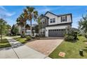 Lovely two-story home featuring a brick driveway, well-manicured lawn, palm trees, and a charming covered porch at 10640 Tibbett St, Orlando, FL 32832