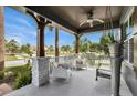 Cozy front porch features stone columns, white railings, comfortable seating, and a ceiling fan at 10640 Tibbett St, Orlando, FL 32832