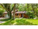 Inviting single-Gathering home boasting a well-manicured lawn, brick accents, and a serene wooded backdrop at 109 Poinciana Ln, Deltona, FL 32738