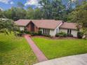 Inviting single-story home with mature trees, manicured lawn, and brick walkway at 207 S Sweetwater Blvd, Longwood, FL 32779
