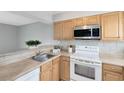 Functional kitchen featuring wood cabinetry, white appliances, and modern microwave at 208 Scottsdale Sq # 208, Winter Park, FL 32792