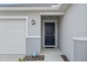 Close-up of a stylish front door and a spacious two-car garage at 232 Summerlin Loop, Haines City, FL 33844