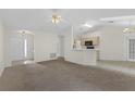 Spacious living room with carpet flooring, complemented by neutral walls, ceiling fan and skylights, open to the kitchen at 2404 Sw 20Th Ter, Ocala, FL 34471