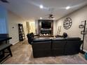 Cozy living room featuring a rustic fireplace, ceiling fan, and comfortable black leather seating at 2564 River Landing Dr, Sanford, FL 32771