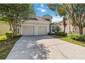 Inviting two-story home with a two-car garage, tiled roof, lush trees, and manicured landscaping at 2616 Bowring St, Kissimmee, FL 34747