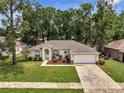 Aerial view of a well-maintained single story home with mature trees and a two-car garage at 2823 Ne 24Th Pl, Ocala, FL 34470