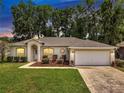 Charming single-story home featuring manicured landscaping and an attached two-car garage at dusk at 2823 Ne 24Th Pl, Ocala, FL 34470